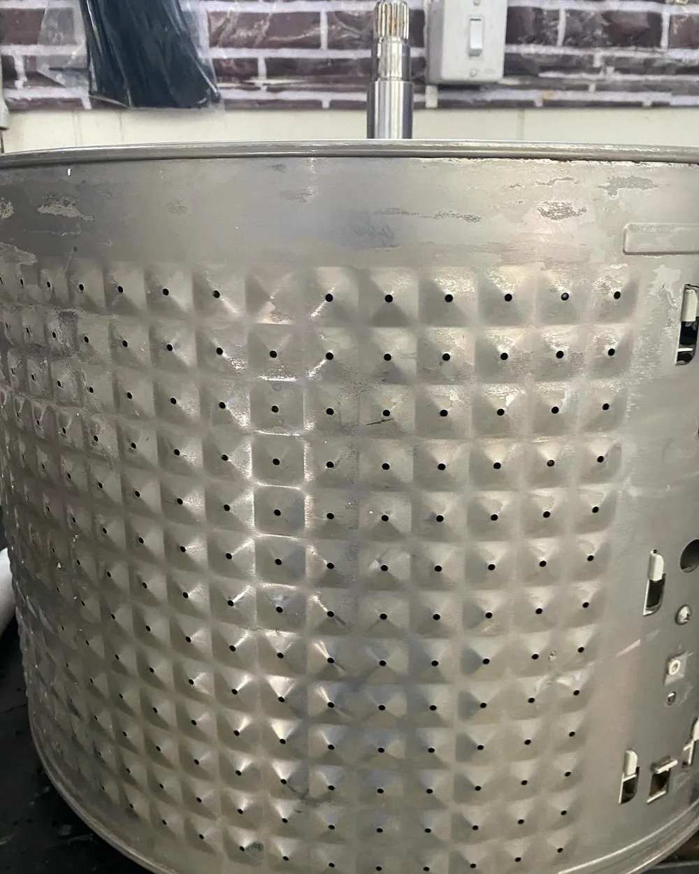 Cesto inox de lavadora fora da máquina durante a manutenção